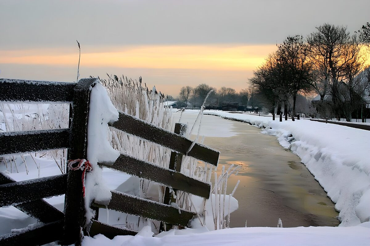 Besneeuwde hek langs sloot