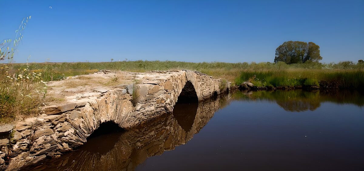 Oude stenen brug bij een kalme waterloop