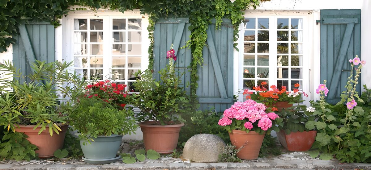 Franse gevel met bloemen, kannen, ramen en blauwe luikjes