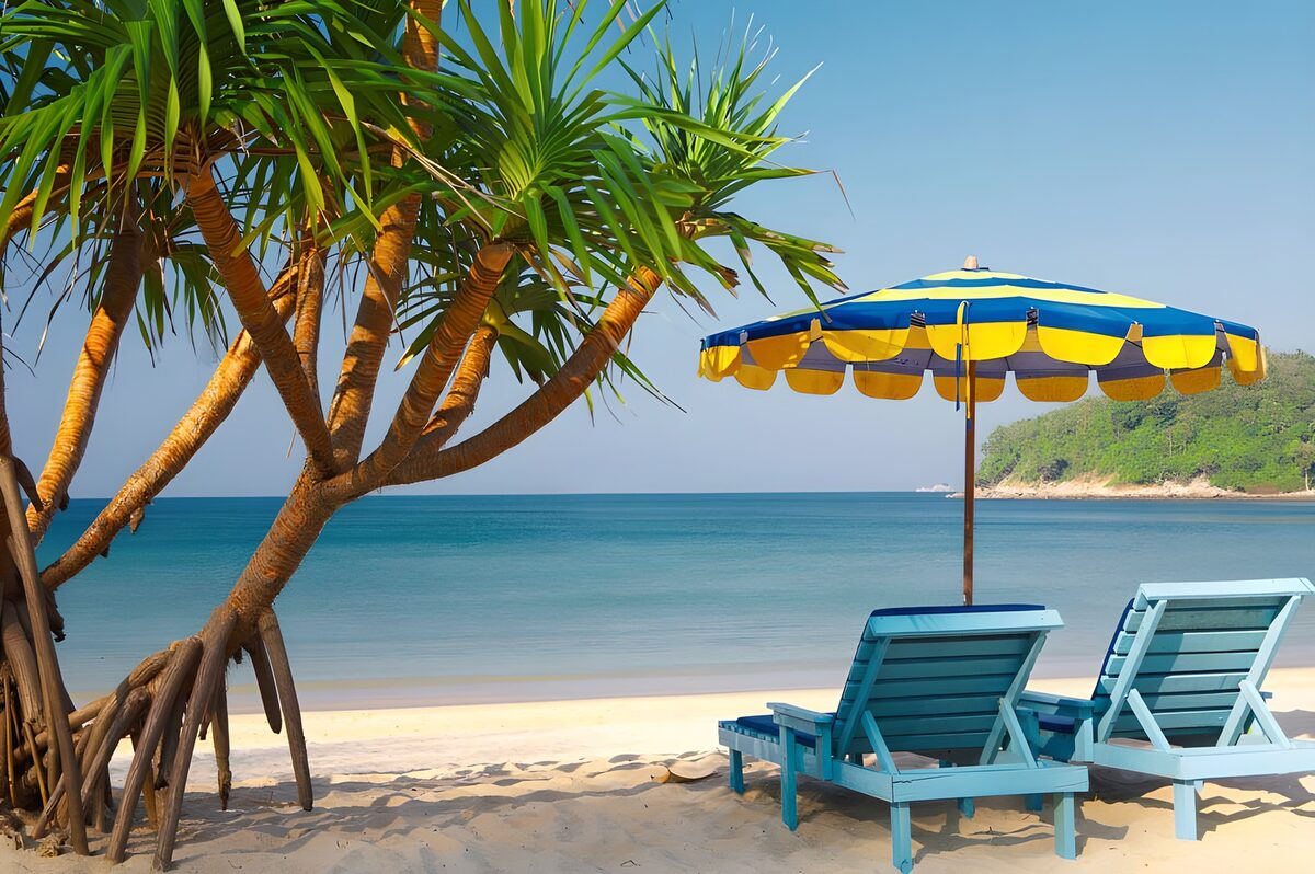 TP21555: Tropische boom op strand met parasol en blauwe ligstoelen